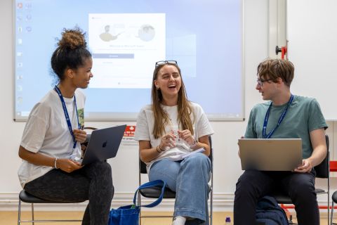 Photo of three students smiling and talking during a outreach visit 