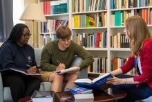 Photo of two students engaged in conversation with a tutor during a tutorial 