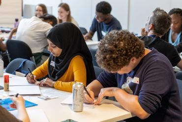 Photo of students writing at tables during an OppOx session