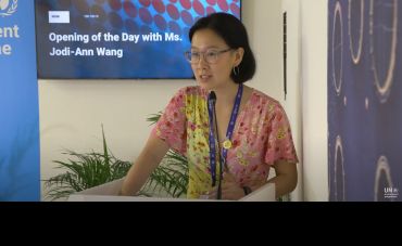 Jodi-Ann Wang, a young Asian lady, speaking at a podium at COP28