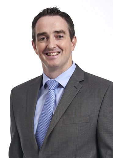 Portrait photograph of Professor Michael McMahon, a middle-aged white man with short dark hair wearing a grey suit.