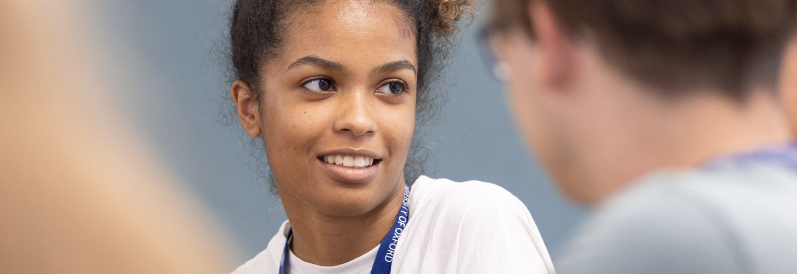 A student smiles whilst speaking to their peers.