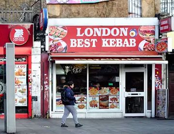 person walking past a kebab shop