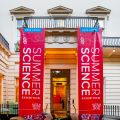 Entrance to The Royal Society’s headquarters in London. The entrance is flanked by two large red banners which each say ‘Summer Science Exhibition.’